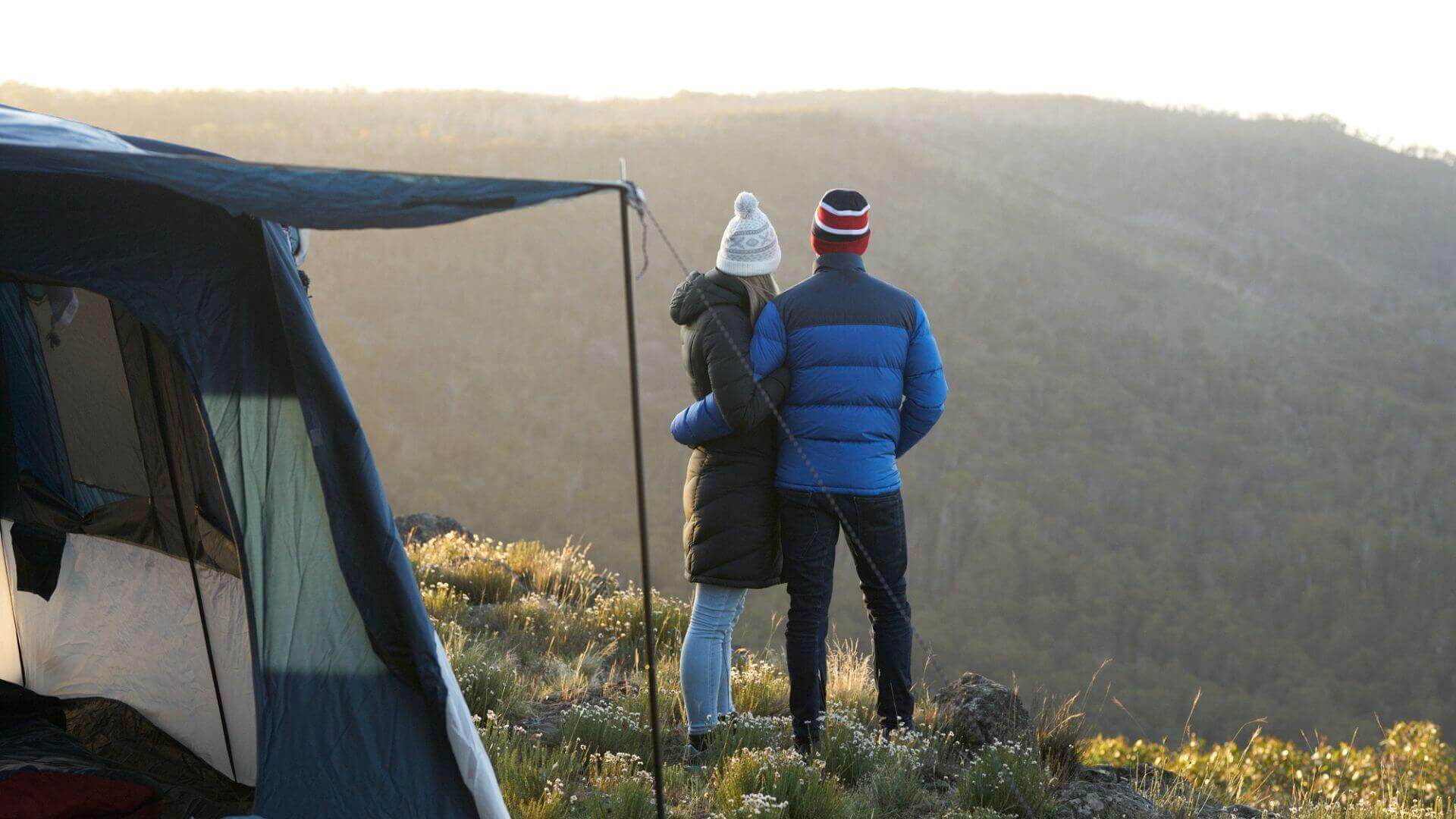 Man & Woman Camping In Puffer Jackets