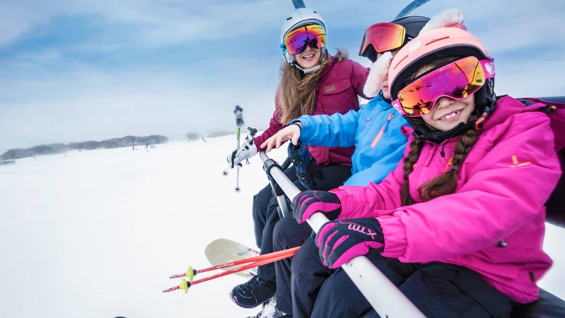 Woman & 2 Kids In Snow Gears Riding A Skii Lift Up The Slopes